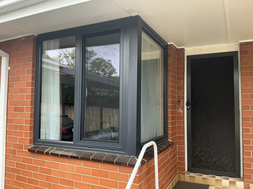 Modern bay window on red brick house with foundation underpinning and rising damp repair.